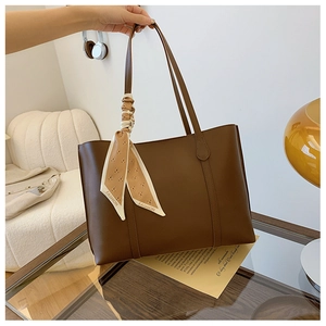 Detail of dark brown leather tote bag with a patterned silk scarf on the handle