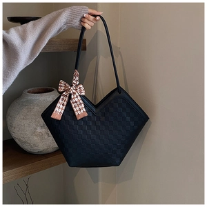 Detail of black embossed tote bag featuring a V-shaped opening and elegant silk scarf decoration