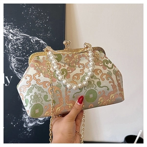 Detail of vintage embroidered crossbody bag with pearl handle and dragon patterns