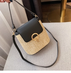 Détail du sac seau en paille avec rabat en cuir noir et boucle en métal doré chic