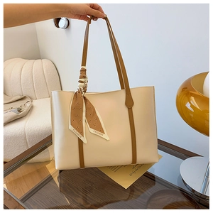 Detail of minimalist cream tote bag with contrast brown straps and bear print silk scarf