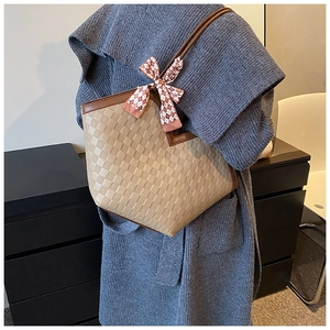 Detail of checkered embossed beige tote bag with a silk scarf tied on the handle
