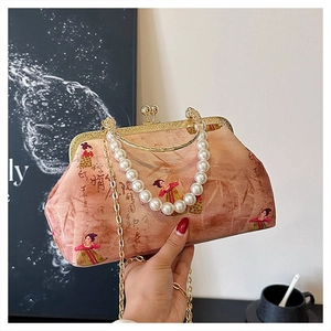 Detail of vintage pink embroidered handbag with pearl handle and metal clasp closure
