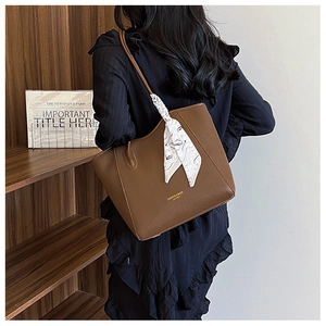 Close-up of brown lychee grain leather tote bag with silk scarf and gold lettering