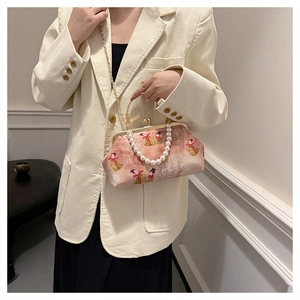 Detailed view of pink crossbody bag with vintage lady embroidery and pearl handle