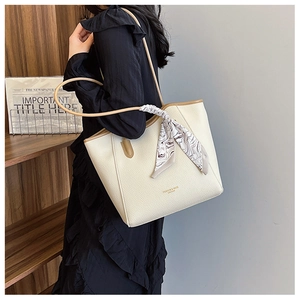 Detail of off-white tote bag with silk scarf on handle and gold foil brand logo