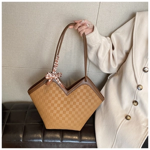Detail of tan embossed tote bag with checkered pattern and decorative silk scarf
