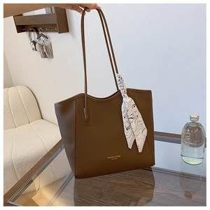 Detail of dark brown lychee leather tote with a silk scarf tied on the handle