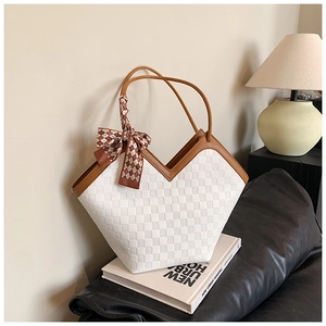 Detailed view of white textured tote bag with silk scarf and brown leather handles
