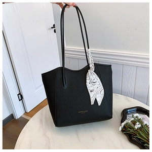 Detail of black pebbled leather tote bag featuring a decorative silk scarf and gold lettering