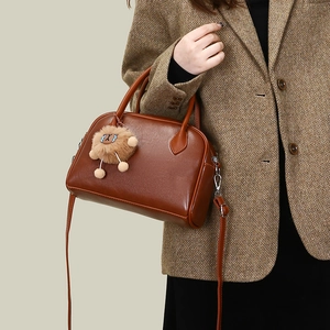 Close-up of retro brown Boston handbag featuring a cute plush lion charm and shoulder strap