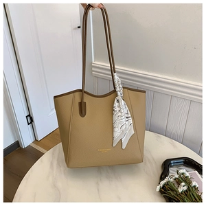 Detail of beige faux leather tote with brown handles and a patterned silk scarf accessory