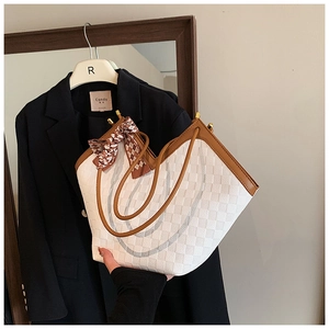 Detail of white checkered tote bag with brown leather trim and decorative silk scarf wrap