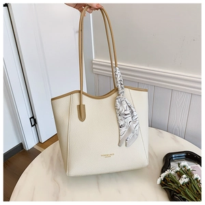 Close-up of beige lychee grain tote bag with brown handles and geometric silk scarf
