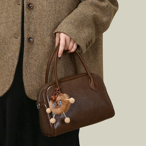 Detailed close-up of a dark brown faux leather bag featuring a cute plush bear pendant accessory