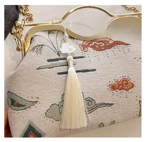 Detail of embroidered jacquard shell bag with pearl rabbit pendant and silk tassel