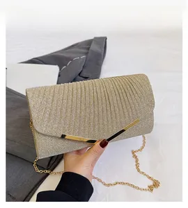 Detail of champagne gold sequin envelope clutch with metallic V-shaped accent and chain