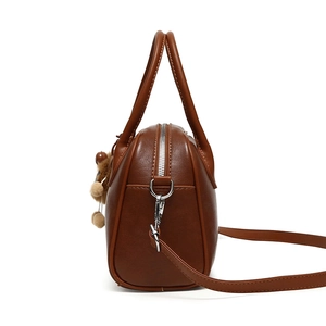 Detail view of deep brown faux leather crossbody bag with silver zipper and side pocket