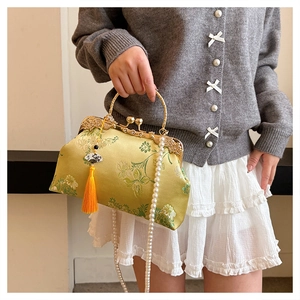 Détails d'un sac jaune avec broderie florale, chaîne en perles et pompon orange