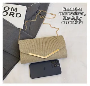 Detail of gold glitter clutch bag with V-shaped metal trim showing smartphone size scale