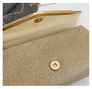 Detail of gold envelope clutch bag featuring magnetic snap closure and metal chain strap