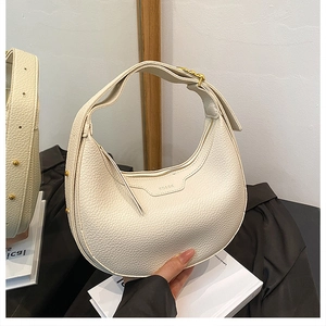 Chic cream white hobo handbag with litchi texture and gold hardware held by hand