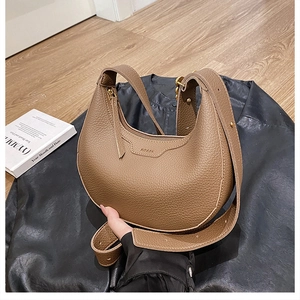 Brown lychee leather half-moon crossbody bag with adjustable strap and gold zipper