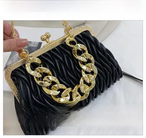Detail of black pleated matelassé evening bag with vintage gold chain and engraved hardware