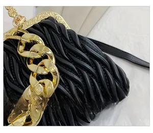 Macro detail of black pleated evening bag with premium glossy texture and gold chain link