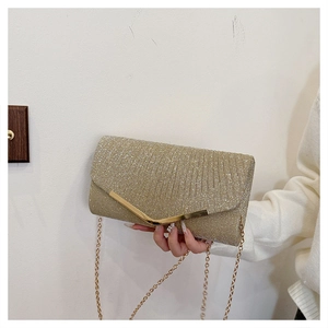 Close-up of sparkling gold sequin envelope clutch with V-shaped metal trim and chain