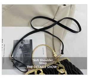 Detail of black pleated evening bag featuring golden ring handle and soft shoulder strap
