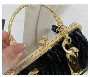 Detail of premium golden metal ring handle and chain on black ruched cloud bag