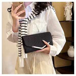 Detailed view of black pleated clutch with V-shaped silver metal trim and chain