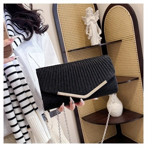 Detail of elegant black pleated evening clutch bag with gold trim and chain strap