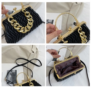 Detail view of black pleated handbag with gold hardware, metal handle and inner lining