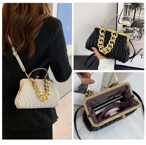 Detail view of the pleat texture, metal clasp, and gold chain of the shell clutch bag