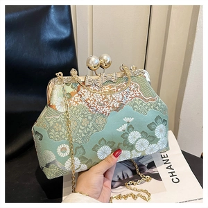 Dettaglio ricamo floreale su borsa vintage con chiusura dorata e perle eleganti