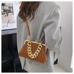 Detail of brown pleated cloud bag with chunky gold chain and retro clasp on gray blazer