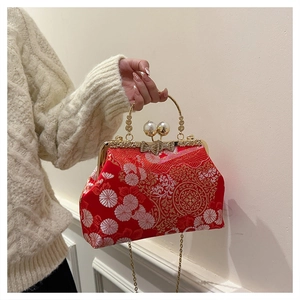 Dettaglio borsa vintage rossa ricamata con chiusura a perla e manico dorato