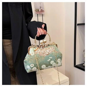 Dettagli ricamo floreale e chiusura a perla su borsa verde con manico dorato di lusso