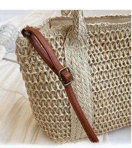 Detail of a smooth adjustable brown leather shoulder strap on a woven straw bag