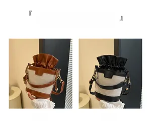 Detail view of two canvas bucket bags in brown and black with drawstring closure