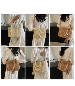 Detail view of woven straw tote bag featuring decorative tassels and dual shoulder straps
