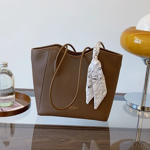 Brown litchi texture leather tote bag with printed silk scarf on a glass desk