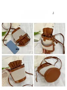 Detail view of canvas bucket bag with brown leather trim and drawstring closure