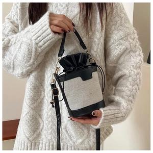 Detail of a minimalist bucket bag featuring contrast leather trim and drawstring closure