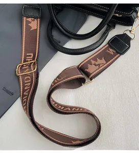 Detail of adjustable patterned woven shoulder strap with gold metal hardware on black tote