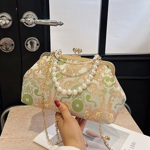 Vintage embroidered crossbody bag with pearl handle and golden chain strap on cream fabric
