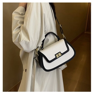Modèle portant un sac à main rétro bicolore noir et blanc avec fermoir pivotant doré