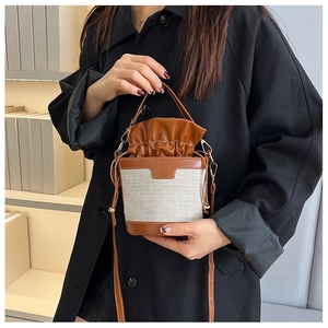 Detail of vintage canvas bucket bag with brown leather trim and drawstring closure